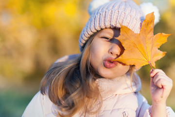 Autumn outdoor portrait of girl holds leaf