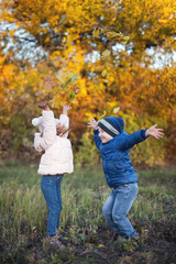 Happy kids walking outdoor at autumn park throw leaves