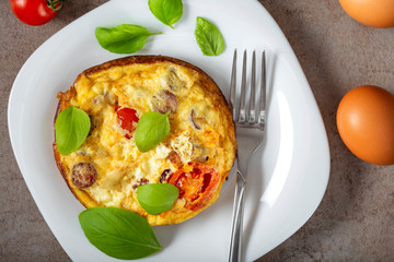 Breakfast food - Omelette with pork sausages, cheese, onion and cherry tomatoes on the white plate