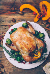 Thanksgiving roasted chicken with Brussels sprouts and spices on a rustic wooden table. Thanksgiving dinner or fall dinner concept background with autumn leaves. Thanksgiving table setting background.