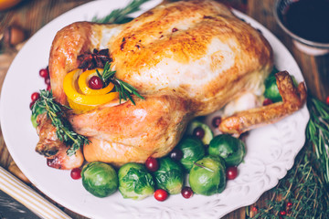 Thanksgiving roasted chicken with Brussels sprouts and spices on a rustic wooden table. Thanksgiving dinner or fall dinner concept background with autumn leaves. Thanksgiving table setting background.
