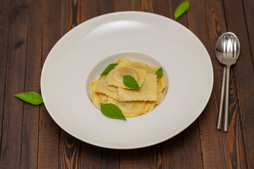 Plate of ravioli with basil on dark background