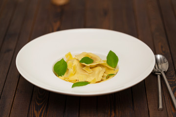 Plate of ravioli with basil on dark background