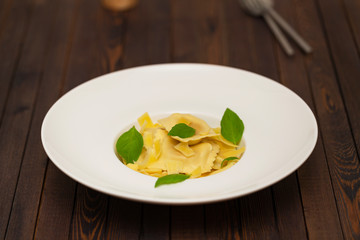 Plate of ravioli with basil on dark background