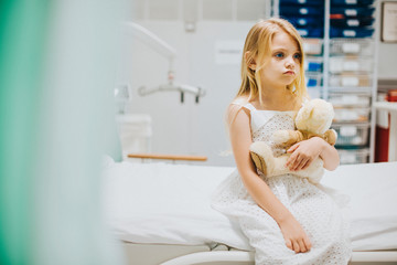 Young girl sitting alone on a hospital bed