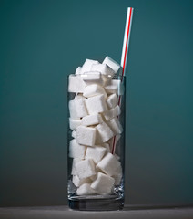 conceptual macro still life image of refreshment glass full of sugar cubes and straw isolated on...