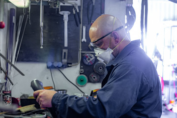 Side view portrait of man working in garage repairing motorcycle and customizing it