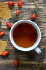 Autumn composition with rose hips nuts leaves a Cup of tea. A Cup of tea with rose hips. Autumn hot drink