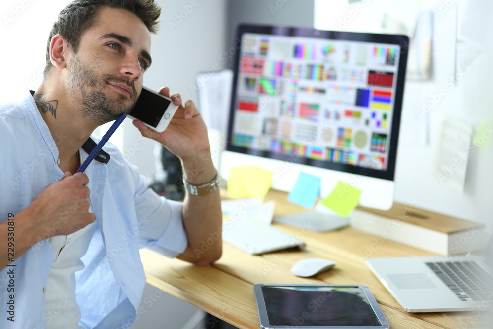 Poster portrait of young designer sitting at graphic studio in front of laptop and computer while working o