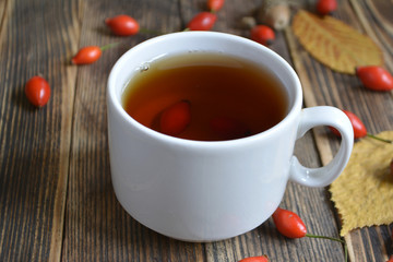 Autumn composition with rose hips nuts leaves a Cup of tea. A Cup of tea with rose hips. Autumn hot drink