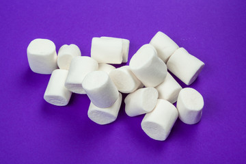 Fototapeta na wymiar marshmallow laid out on violet paper background.