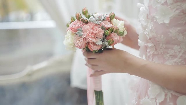 A young girl in a wedding dress picked up a wedding bouquet. Close-up