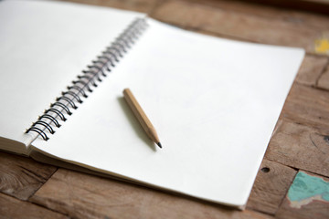 Pencil on empty notebook on wooden table