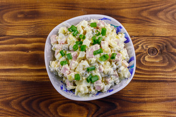 Traditional Russian festive salad Olivier on wooden table. Top view