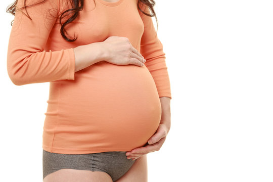 お腹の中の胎児に愛情を注ぐオレンジ色のシャツを着た臨月の妊婦