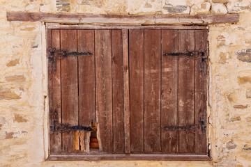 Antique wooden shutters in an ancient limestone wall.Damaged closed blinds.