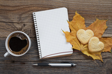 Notebook, pen, coffee with cookies and autumn leaf