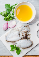 Fresh cuttlefish and ingredients for preparing cooking for pasta or rice with squids or cuttlefish, parsley and broth.