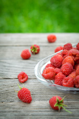  Pink fresh raspberries on an glass vessel on a gray wood background in the garden on the background of green grass Berry Fruit Sadovina Healthy Food hack close up