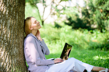 Obraz premium Woman with laptop work outdoors lean tree. Minute for relax. Education technology and internet concept. Girl work with laptop in park sit on grass. Natural environment office. Work outdoors benefits