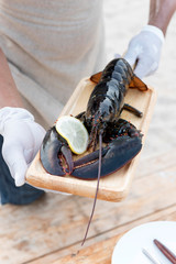 Lobster in wooden plate holding by hand