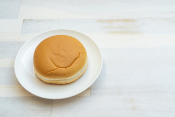 Burger roll on a plate, wooden background and copy space