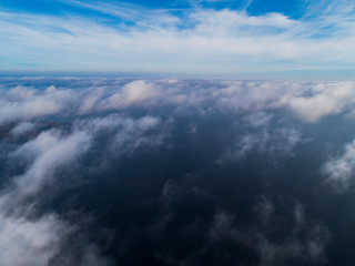 Naklejka na ściany i meble Aerial view White clouds in blue sky. Top view. View from drone. Aerial bird's eye view. Aerial top view cloudscape. Texture of clouds. View from above. Sunrise over the sea