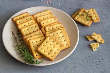 Thin crispy salted crackers with seeds and herbs on grey concrete background. 