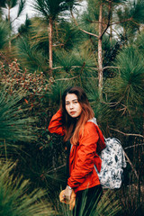 Traveler girl with backpack in the pine forest. Warm tone preset.