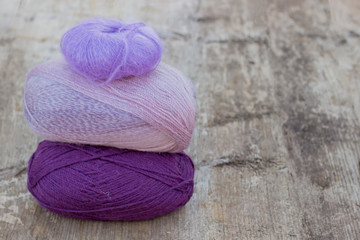 three skeins of yarn of different colors on the wooden surface of gray. background texture