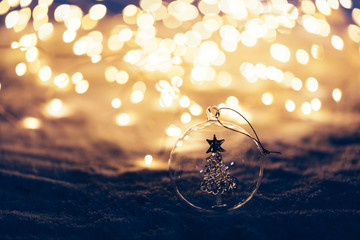 Christmas ornament on snowy illuminated background.