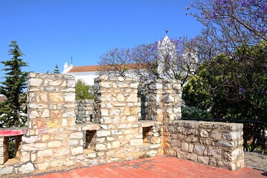 View of castle battlements with St Marys church (Igreja de Santa Maria do Castelo) to the rear, Tavira, Algarve, Portugal.