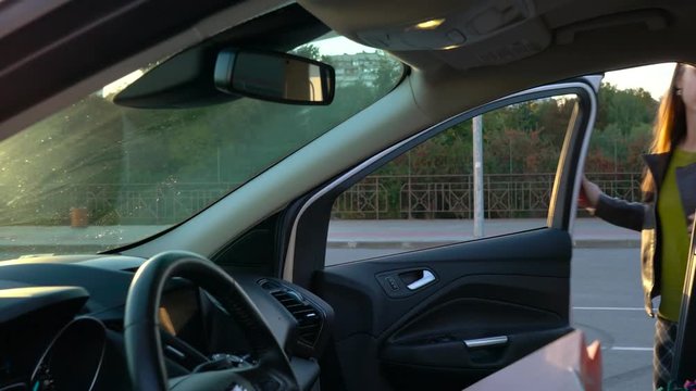 Woman puts shopping bags on a car seat and sits in it, intending to drive away.