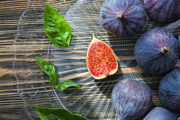 Plate with fresh ripe figs and basil on wooden table