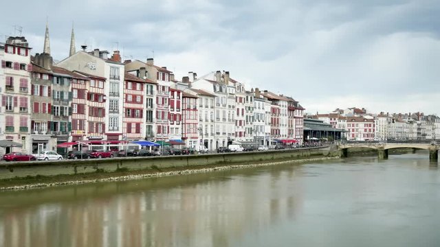 Time lapse in Bayonne, a city in southwestern France. View on the Nive river which crosses the city. On the quays there are typical half-timbered houses. Filmed in october 2018. Cloudy sky.