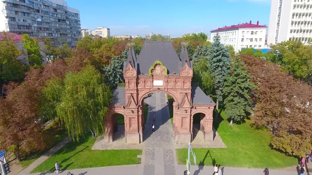 Aerial view cityscape, Russia transport traffic on Place Alexander Arc autumn day. Avenue street in Krasnodar 4K aerial drone footage overhead car road through avenue of trees camera move back up.