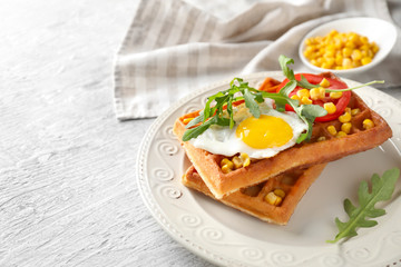 Delicious waffles with fried egg and vegetables on plate
