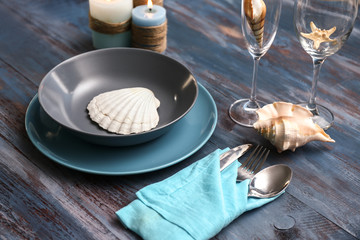 Beautiful table setting with sea shells on wooden background