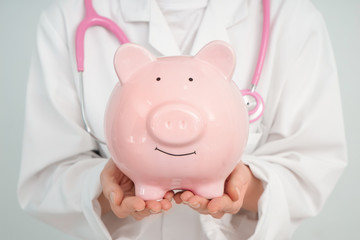 Female doctor holding piggy bank, closeup
