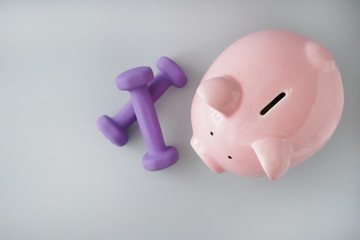 Piggy bank with dumbbells on light background. Weight loss concept