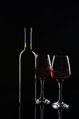 Bottle and glasses of red wine on dark background
