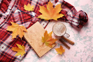 Composition with cup of aromatic coffee, warm shirt, book and autumn leaves on color background
