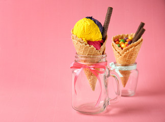 Waffle cone with delicious ice cream in mason jar on color background