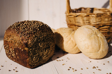 Assortment of baked bread on white wooden table background, hard light