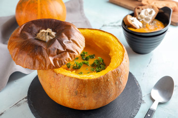 Tasty cream soup served in pumpkin on light table