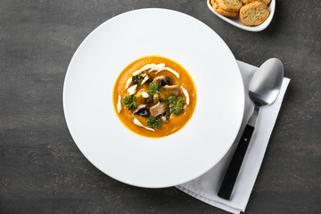 Plate with tasty pumpkin cream soup on grey table