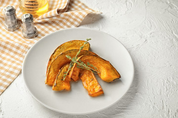 Plate with tasty baked pumpkin pieces on white table