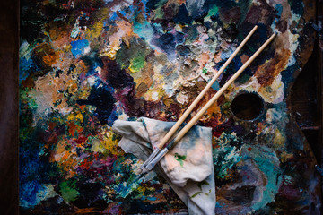 a real artist's palette, oil paints and two paint brushes