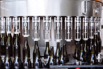 Glass bottles on the automatic conveyor line at the champagne or wine factory. Plant for bottling alcoholic beverages.