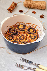 Traditional Hungarian pastry for Thanksgiving and Christmas - poppy seed rolls with chocolate topping in the baking dish decorated with spices. Cinnamon sweet bread on the gray kitchen background.